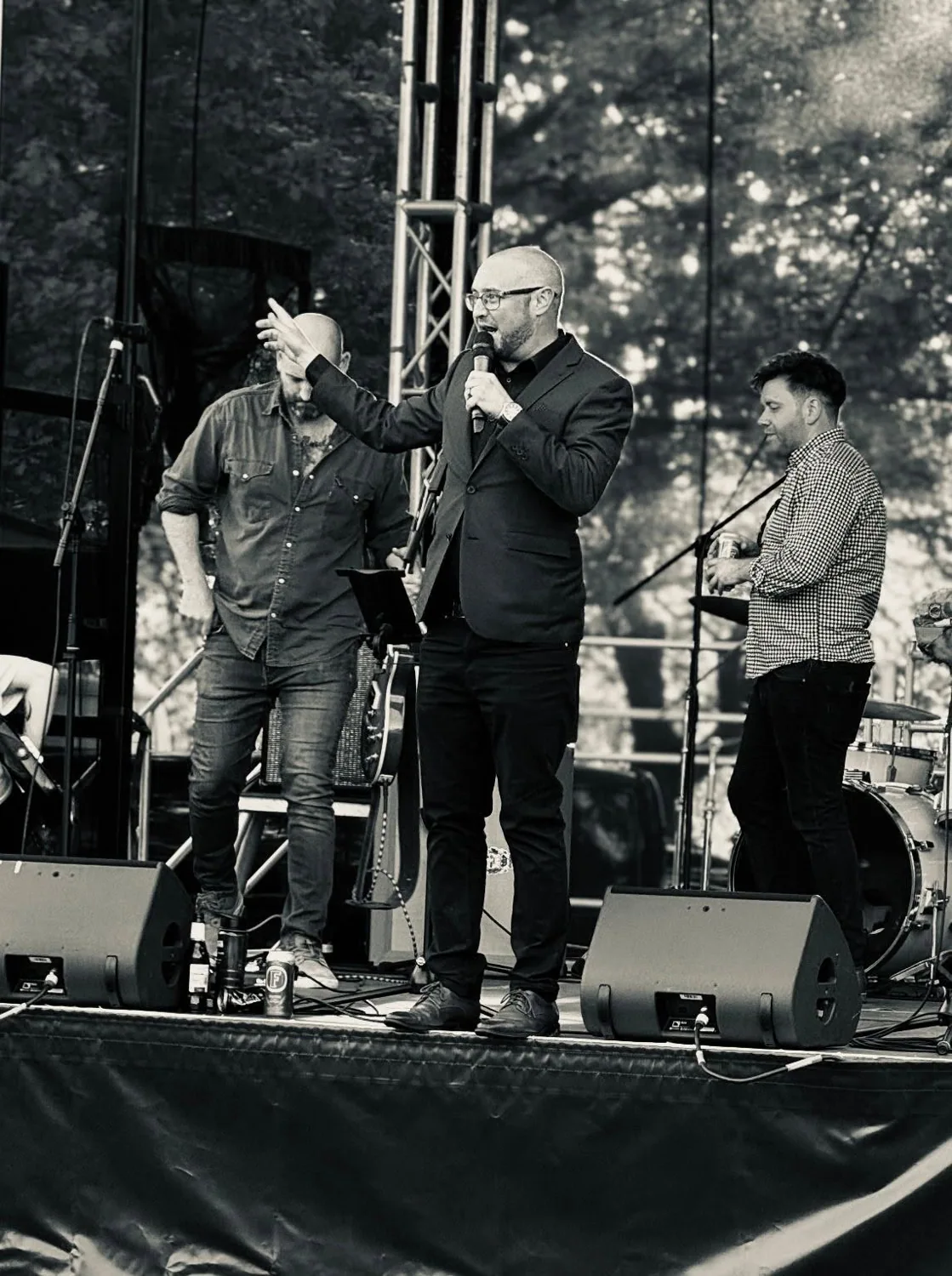 Bradley presenting live on an outdoor stage, photographed in black and white